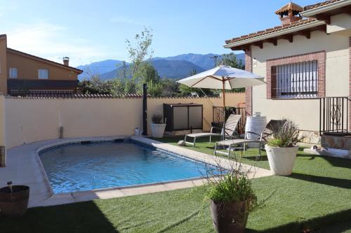 una piscina en un patio con sombrilla en Casa en sierra de gredos piscina privada, en La Adrada