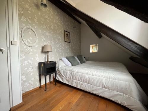 ein Schlafzimmer mit einem Bett und einem Tisch mit einer Lampe in der Unterkunft Le nid Mésange in Alligny-en-Morvan