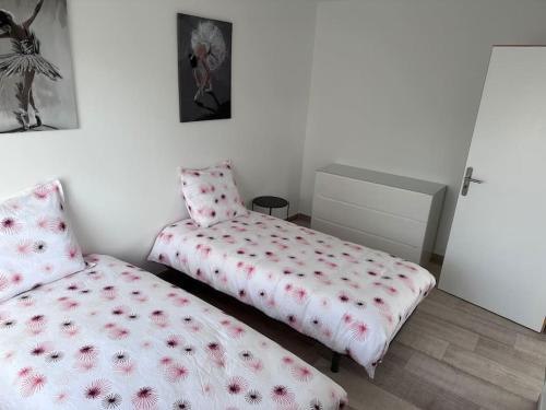 - une chambre avec 2 lits et un couvre-lit orné de fleurs rouges dans l'établissement Chez sana, à Saint-Dizier