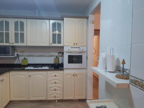 a kitchen with white cabinets and white appliances at DEPARTAMENTO PLANTA BAJA in Villa Nueva