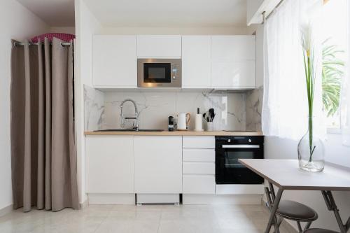 uma cozinha com armários brancos e uma mesa em Magnifique Studio à Beaulieu-sur-mer em Beaulieu-sur-Mer