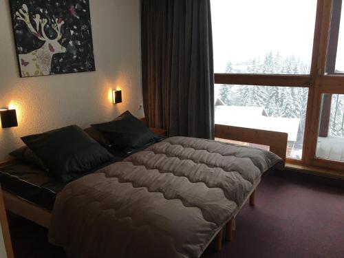 un lit dans une chambre avec une grande fenêtre dans l'établissement Appartement spacieux 10 pers · Ski aux pieds · Balcon · Wifi gratuit · Pieds des commerces - FR-1-346-399, à Arc 1800
