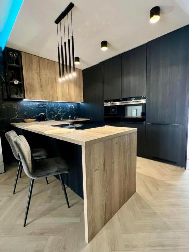 a kitchen with black cabinets and a counter with a chair at 8 Apartment BREZY VYSOKÉ TATRY in Stará Lesná