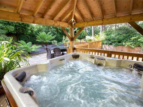 a hot tub in a patio under a wooden umbrella at Hot Tub/Football Court/Sleeps 12/Luxury Villa in Parkstone