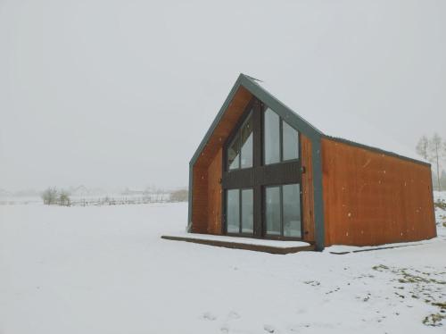 a small wooden building in a snow covered field at Górska Stodoła in Lipowa