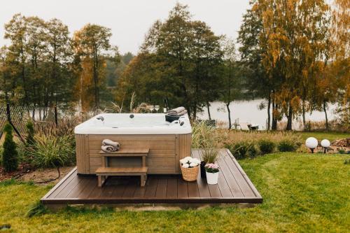 a bath tub sitting on a wooden deck in a yard at Kalwa Lake House - dom nad jeziorem z prywatnym pomostem i jacuzzi oraz sprzętem wodnym in Pasym