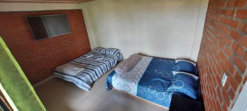 a small bedroom with two beds and a brick wall at Hostel paraiso de colores in Popayan