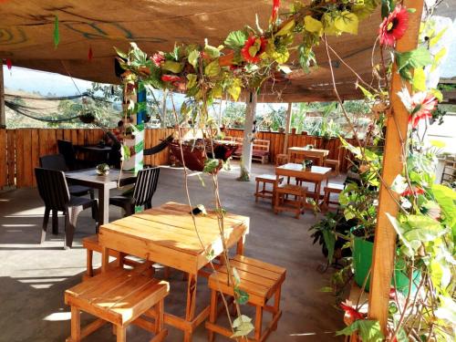 un patio con mesas de madera, sillas y flores en Hostel paraiso de colores, en Popayán