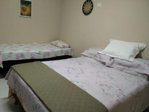 2 łóżka pojedyncze w pokoju z zegarem na ścianie w obiekcie Suíte Aconchego dos Milagres w mieście São Miguel dos Milagres