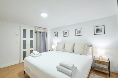 ein weißes Schlafzimmer mit einem großen weißen Bett mit weißen Kissen in der Unterkunft Lovely Apartments - Alójate en el corazón de Madrid in Madrid
