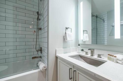 a bathroom with a sink and a tub and a mirror at Treeline by Outpost Whistler in Whistler