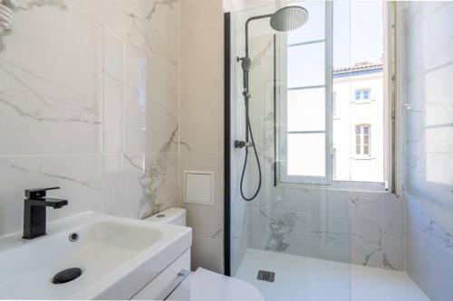 La salle de bains blanche est pourvue d'une douche et d'un lavabo. dans l'établissement Appartement entier haut de gamme, à Bordeaux