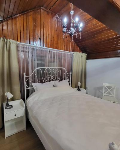 a bedroom with a large white bed and a chandelier at Adac Boutique Hotel in Bucharest