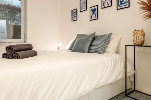 ein Schlafzimmer mit einem weißen Bett mit Kissen darauf in der Unterkunft Appartement 2 chambres in Lüttich
