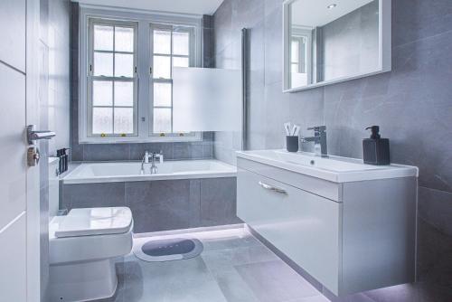 a white bathroom with a sink and a toilet at Artsy Serviced Apartments - Victoria in London