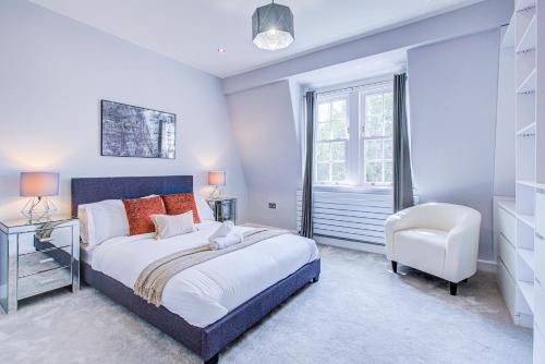 a bedroom with a bed and a chair and a window at Artsy Serviced Apartments - Victoria in London