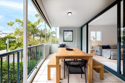 a room with a balcony with a wooden table and chairs at Central Location Stylish 3 Bed with Pool - Sunshine Central in Sunshine Beach