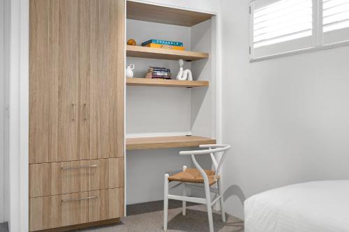 a bedroom with a wooden cabinet and a chair at Central Location Stylish 3 Bed with Pool - Sunshine Central in Sunshine Beach