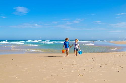 two children standing on a beach holding hands at Central Location Stylish 3 Bed with Pool - Sunshine Central in Sunshine Beach