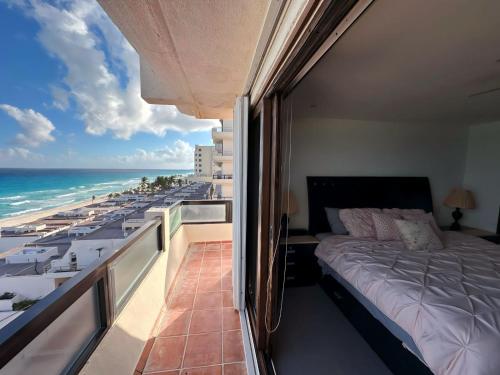 a bedroom with a bed and a balcony with the ocean at Amazing beachfront apartment in Cancún