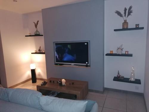 a living room with a couch and a flat screen tv at Appartement paisible entre terre et mer in Cabrières