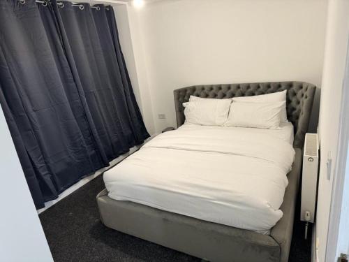1 cama con sábanas blancas y almohadas en una habitación en LUXURY APARTMENTS en Dagenham