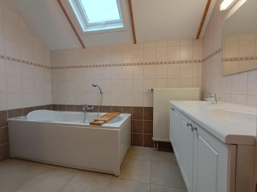een witte badkamer met een bad en een wastafel bij Maison des Fées d'Achouffe in Houffalize