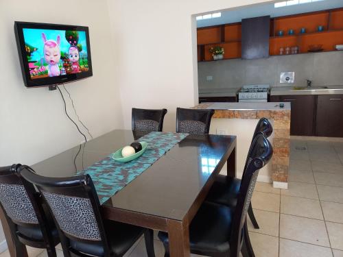 mesa de comedor con sillas y TV en la pared en Apart LAS HERAS en Río Cuarto