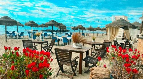 uma praia com mesas, cadeiras e guarda-sóis em SUNSET BEACH em Fiumicino