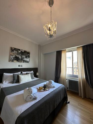 a bedroom with two beds with towels and a chandelier at 2 BD Apt in Syntagma with Acropolis view in Athens