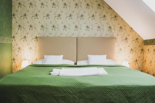 a bedroom with a green bed with two white pillows at Hotel Lipa in Bojnice