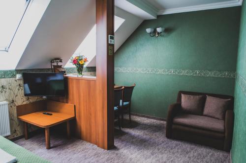 a living room with a tv and a chair and a table at Hotel Lipa in Bojnice