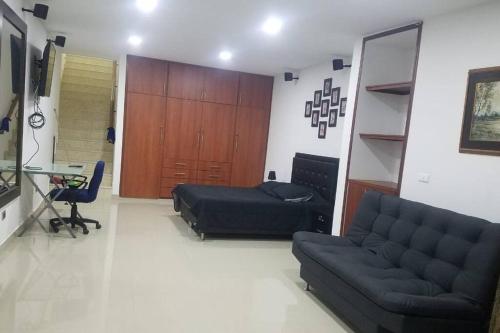 a living room with a couch and a bed and a desk at Hospedajes Pilarica in Medellín