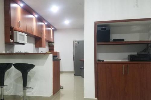 una cocina con armarios de madera y una encimera con taburetes negros en Confort en zona ecológica, Loft en Pilarica 2, en Medellín