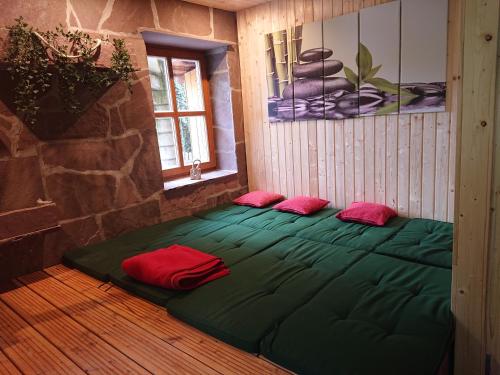 Zimmer mit einem großen grünen Bett mit zwei roten Kissen in der Unterkunft Im Buchenwäldchen in Gleichen