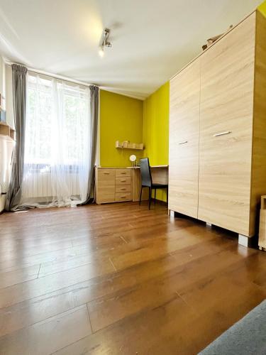 an empty living room with a wooden floor and yellow walls at Cosy room Aleja Kijowska in Krakow