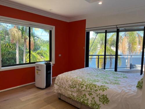 a bedroom with red walls and a bed and two windows at Water Front House in Sydney