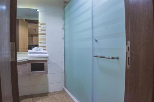 a bathroom with a shower and a sink with towels at Vendome Apartment Lusail in Lusail