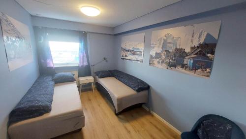 a small room with two beds and a window at Ilulissat Apartment in Ilulissat