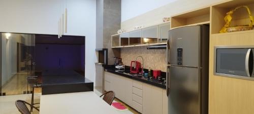a kitchen with a stainless steel refrigerator and a tv at Recanto da Tairine in Olímpia
