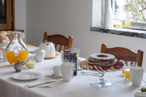 a table with a white table cloth with a cake and orange juice at Beachouse - Surf, Bed & Breakfast in Ericeira