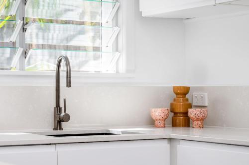 a white kitchen with a sink and a window at La Playa Byron in Byron Bay