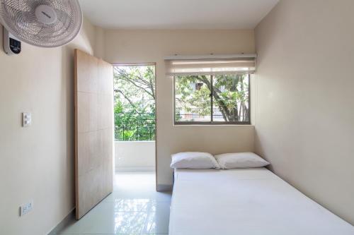 ein weißes Zimmer mit einem Bett und einem Fenster in der Unterkunft CASA TURISTICA MACHU PICCHU MEDELLIN in Medellín