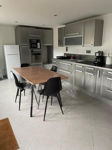 une cuisine avec une table en bois et des chaises noires dans l'établissement Proximité de Douai, à Flers-en-Escrebieux