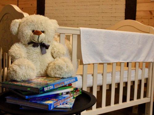 a teddy bear sitting on a stack of books in a crib at Bilychi - садиба у Карпатах in Bilichi