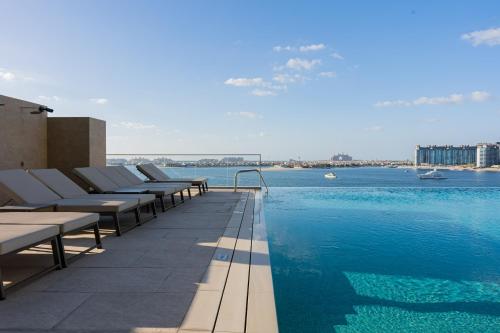 a pool with chaise lounge chairs next to the water at YOUR STAY APARTMENTS Luxury Beachfront Living in Dubai