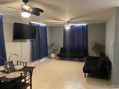 ein Wohnzimmer mit schwarzen Möbeln und einem Flachbild-TV in der Unterkunft Casa Ciruelos Relax Confort and Relax in Ciudad Madero