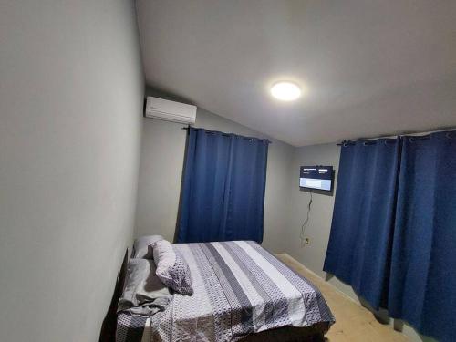 1 dormitorio pequeño con cortinas azules y 1 cama en Casa Ciruelos Relax Confort and Relax, en Ciudad Madero