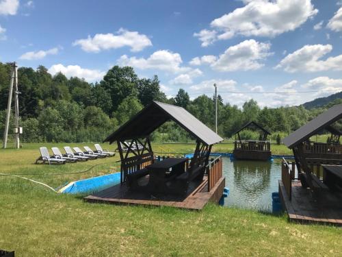 a dock with chairs and a pool in the water at Bilychi - садиба у Карпатах in Bilichi