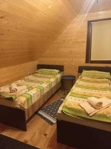 Duas camas num quarto com paredes de madeira em Brvnare Libero TARA em Bajina Bašta
